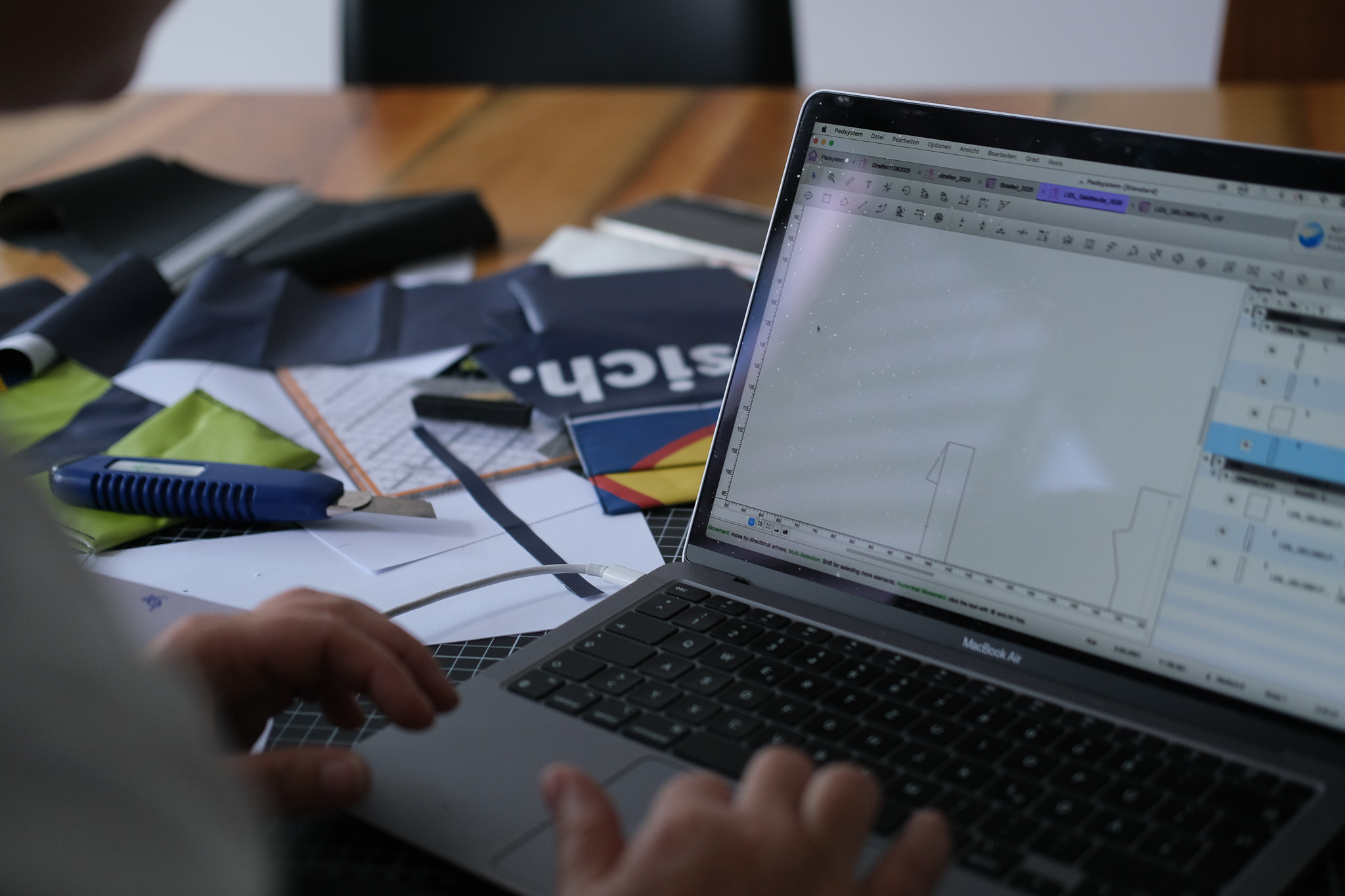 Digitale Schnittentwicklung am Rechner, daneben Materialien und Zuschnitt – Design und Produktion aus einer Hand bei manomama