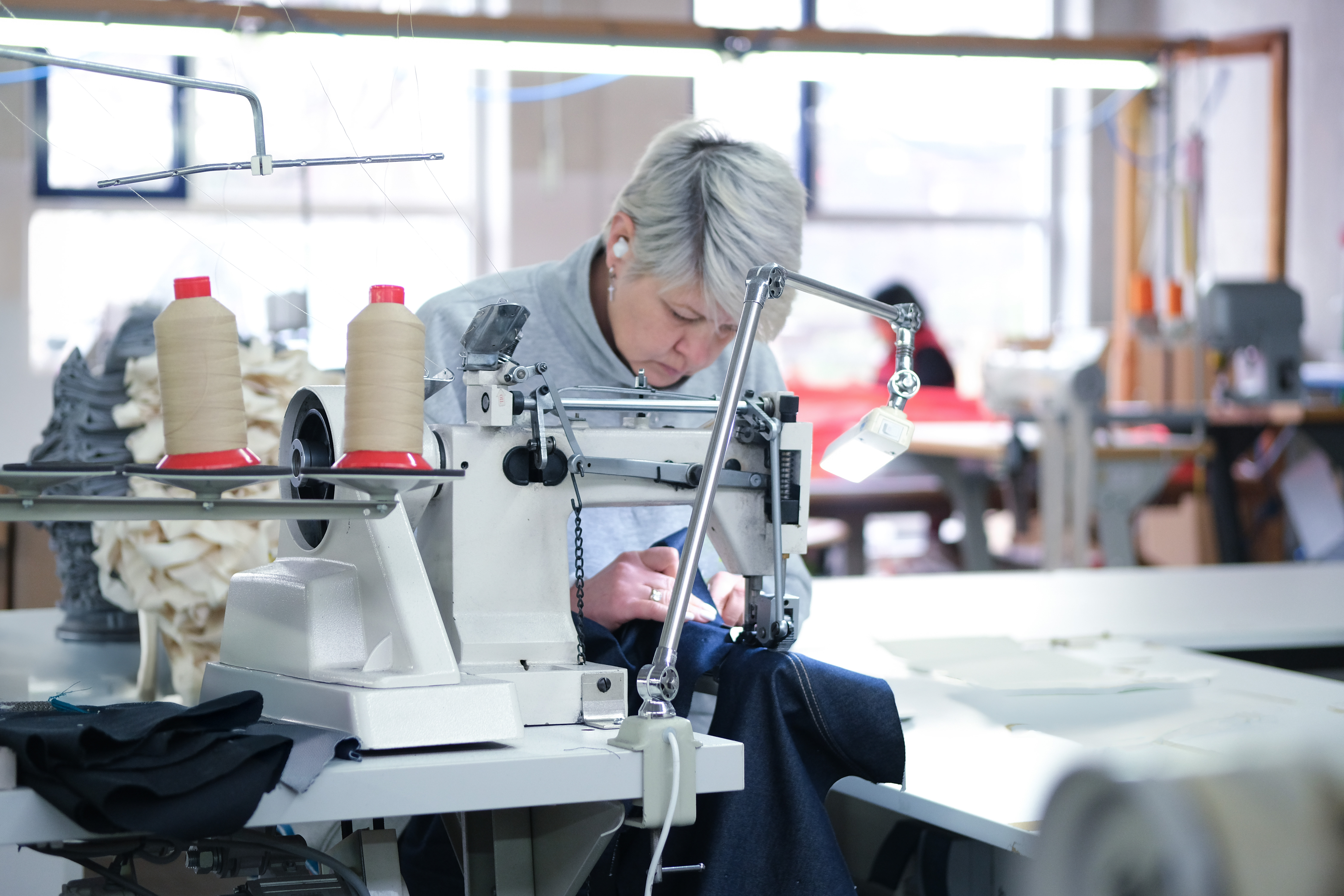 Elena an der Nähmaschine bei der Denim-Produktion – manomama Augsburg