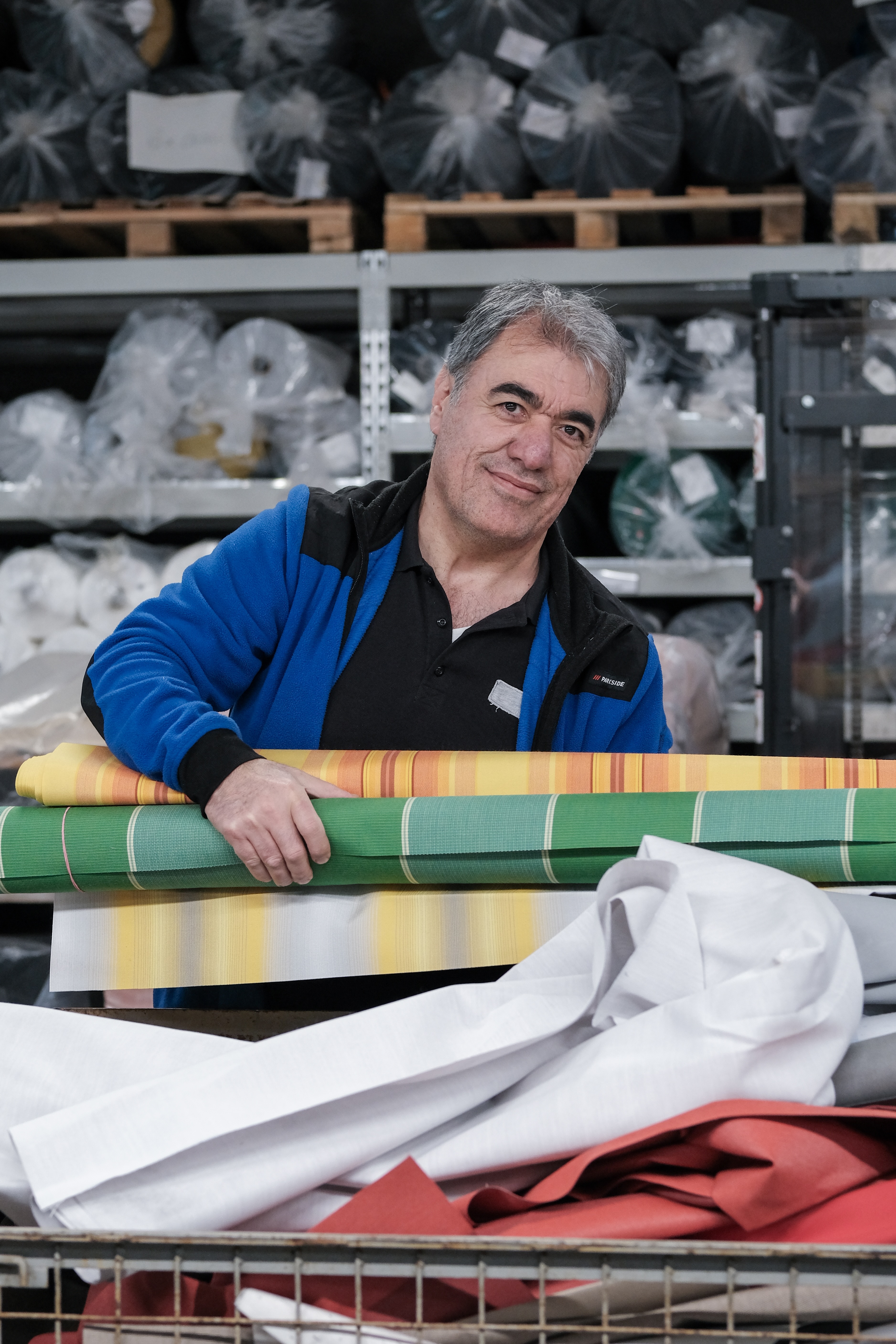 Süley mit Stoffrollen im Materiallager – manomama Augsburg
