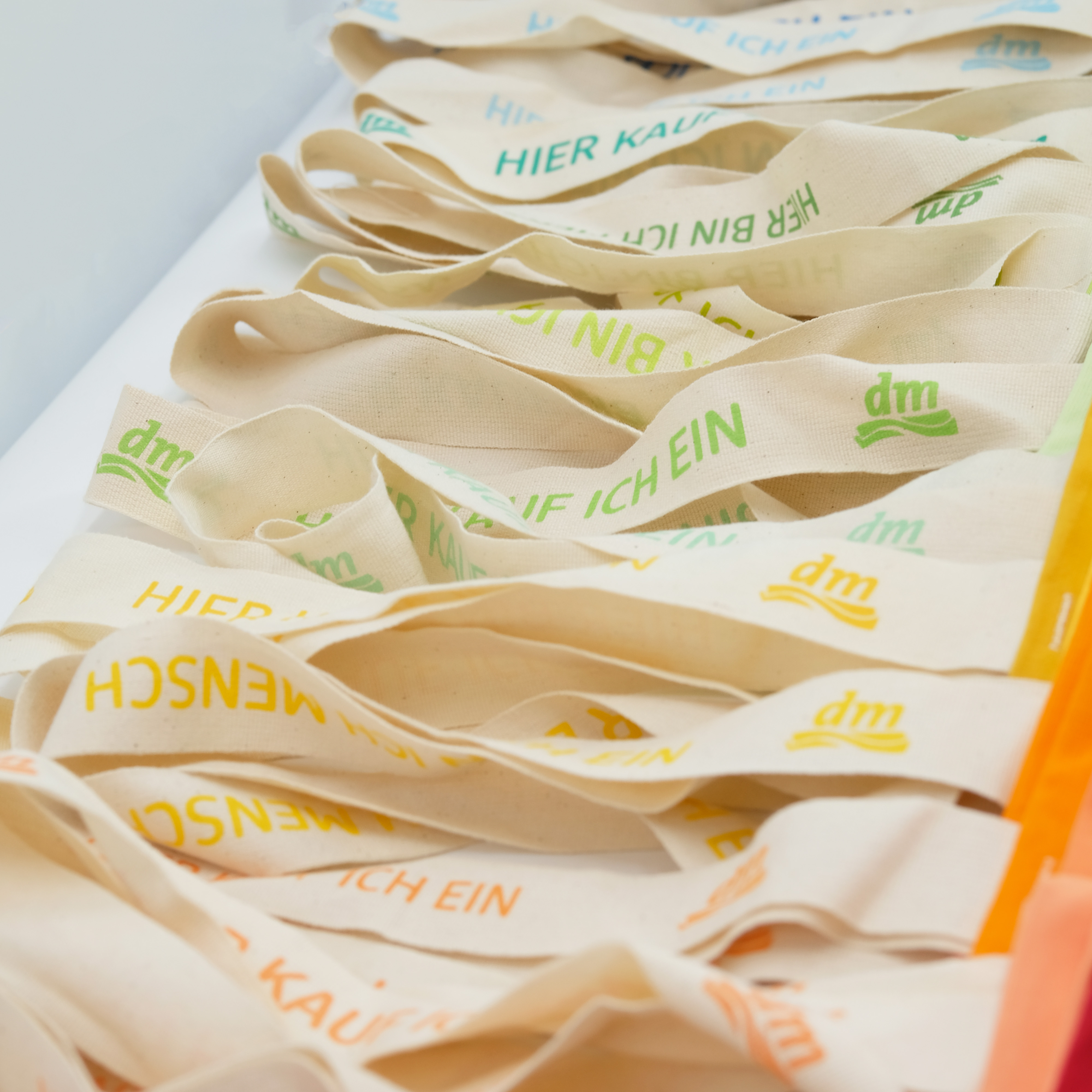dm-Einkaufstaschen mit bunten Trägern und Logo – frühere manomama-Produktion