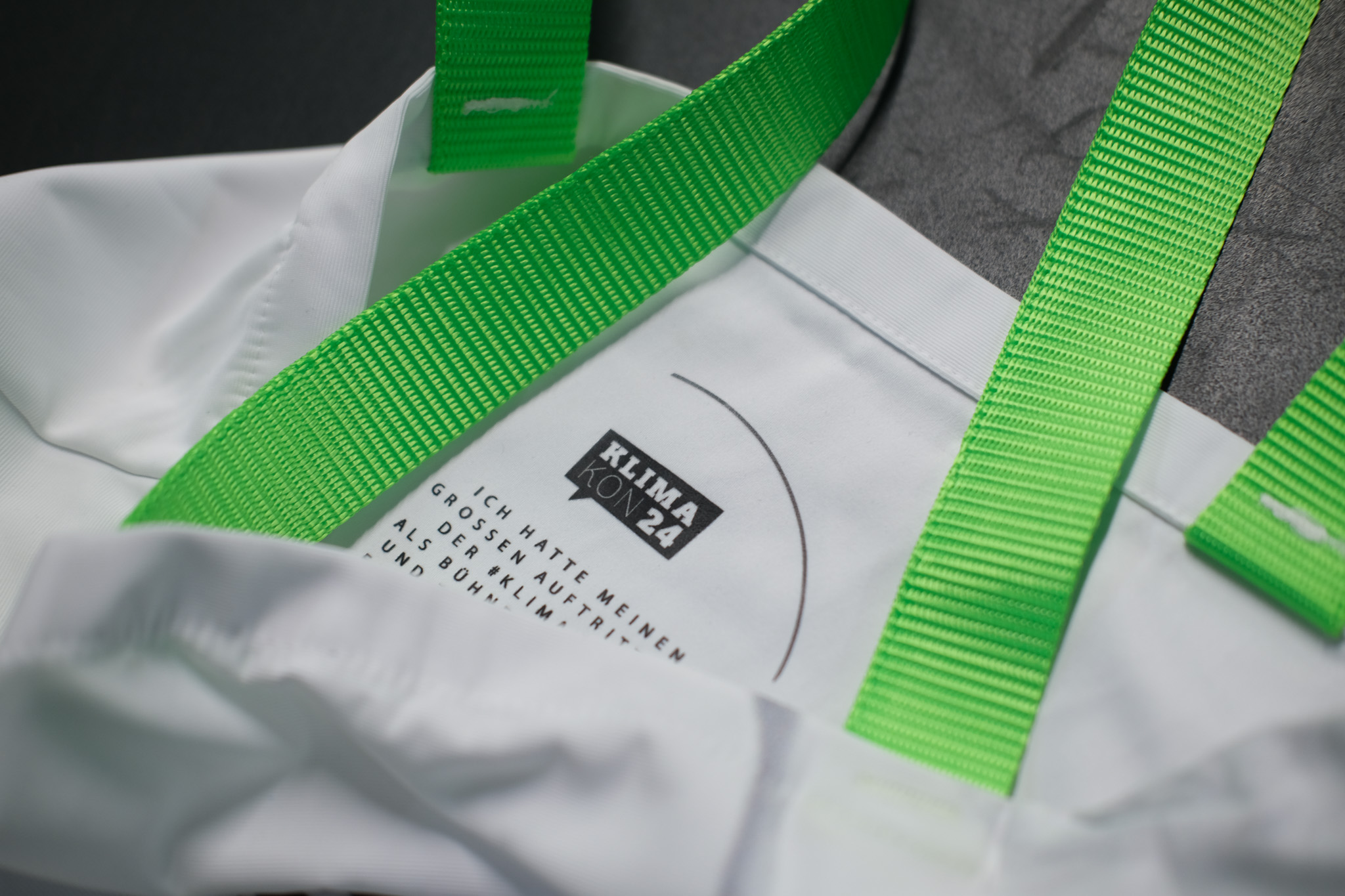 Weiße Upcycling-Tote „KLIMA KON 24“ mit grünen Trägern – manomama