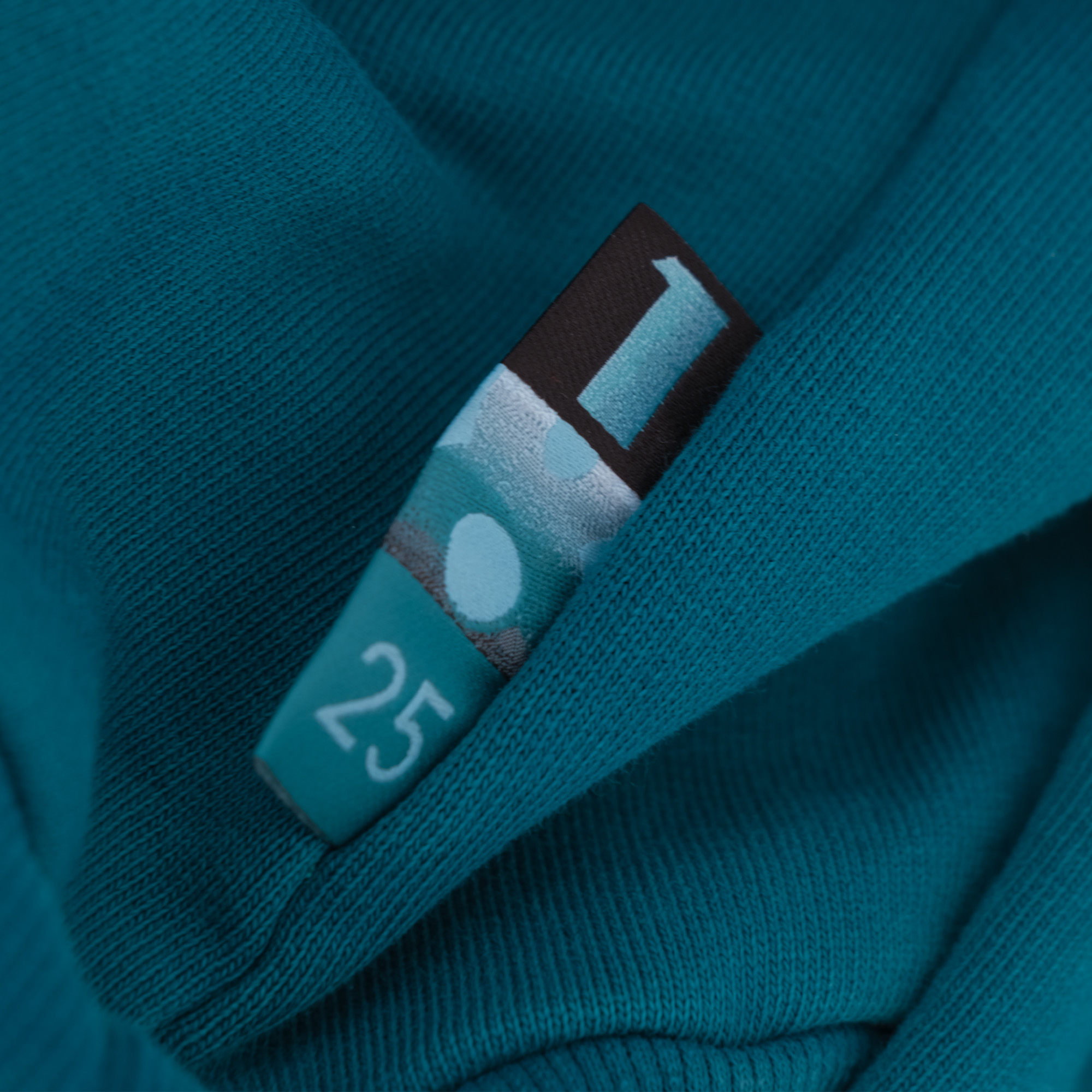Gewebtes Etikett in der Naht eines petrolfarbenen Sweaters – manomama